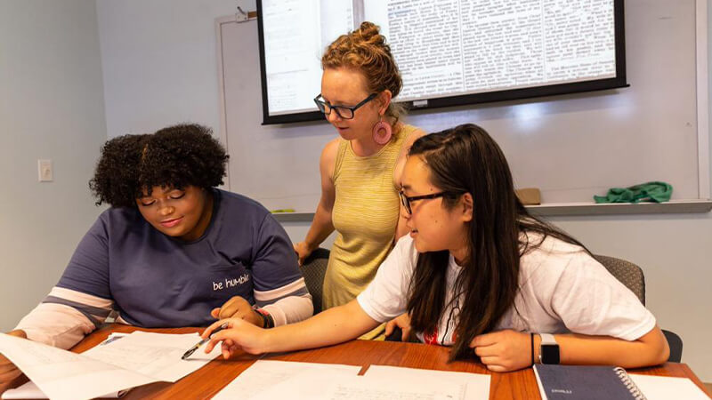 Students look over research project with faculty member
