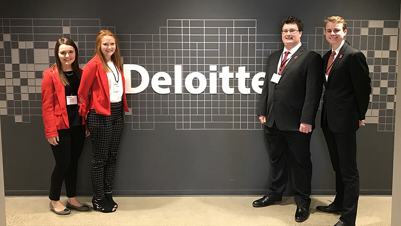 Students standing in front of Deloitte sign