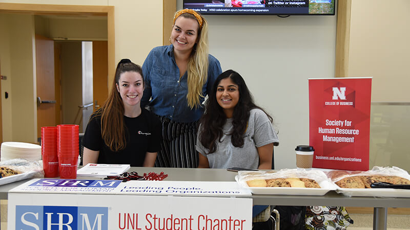 Three students pose at table for Society of Human Resource Management.