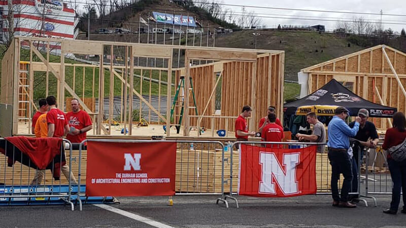 House framing demonstration with UNL Engineering banner hanging on barricade.