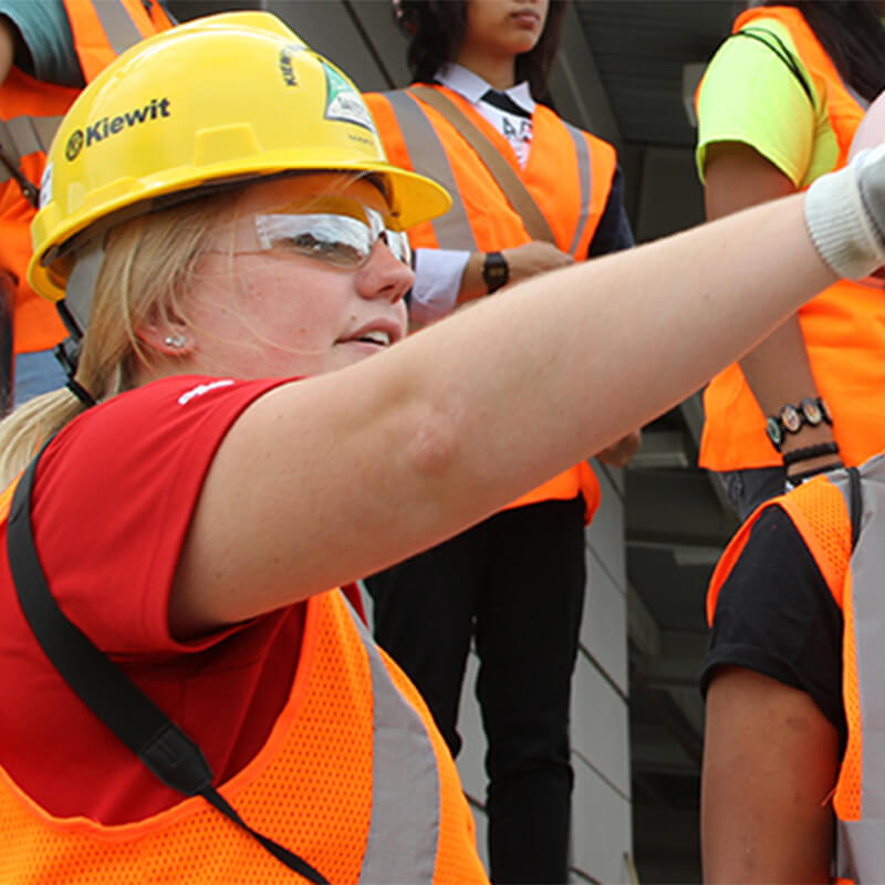 Student in high-vis vest pointing