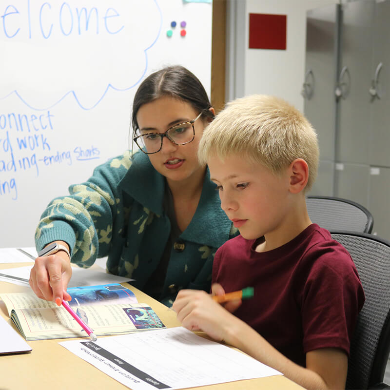 Student working with elementary student in classroom