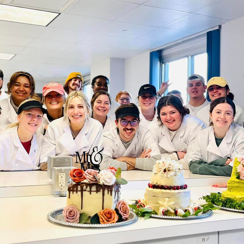 Students posing in front of dessert creations