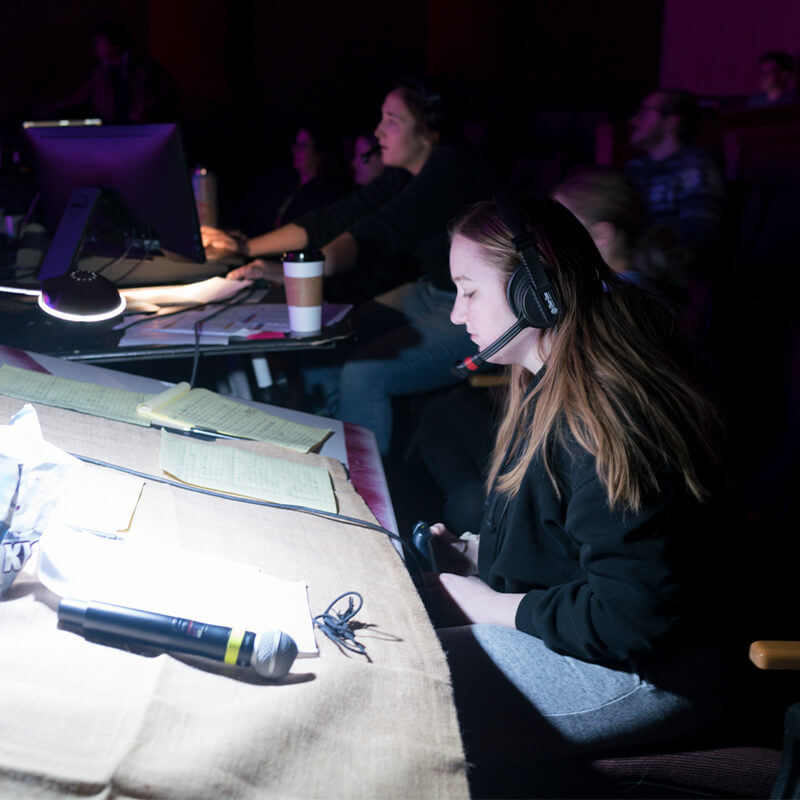 Students backstage looking at sheets