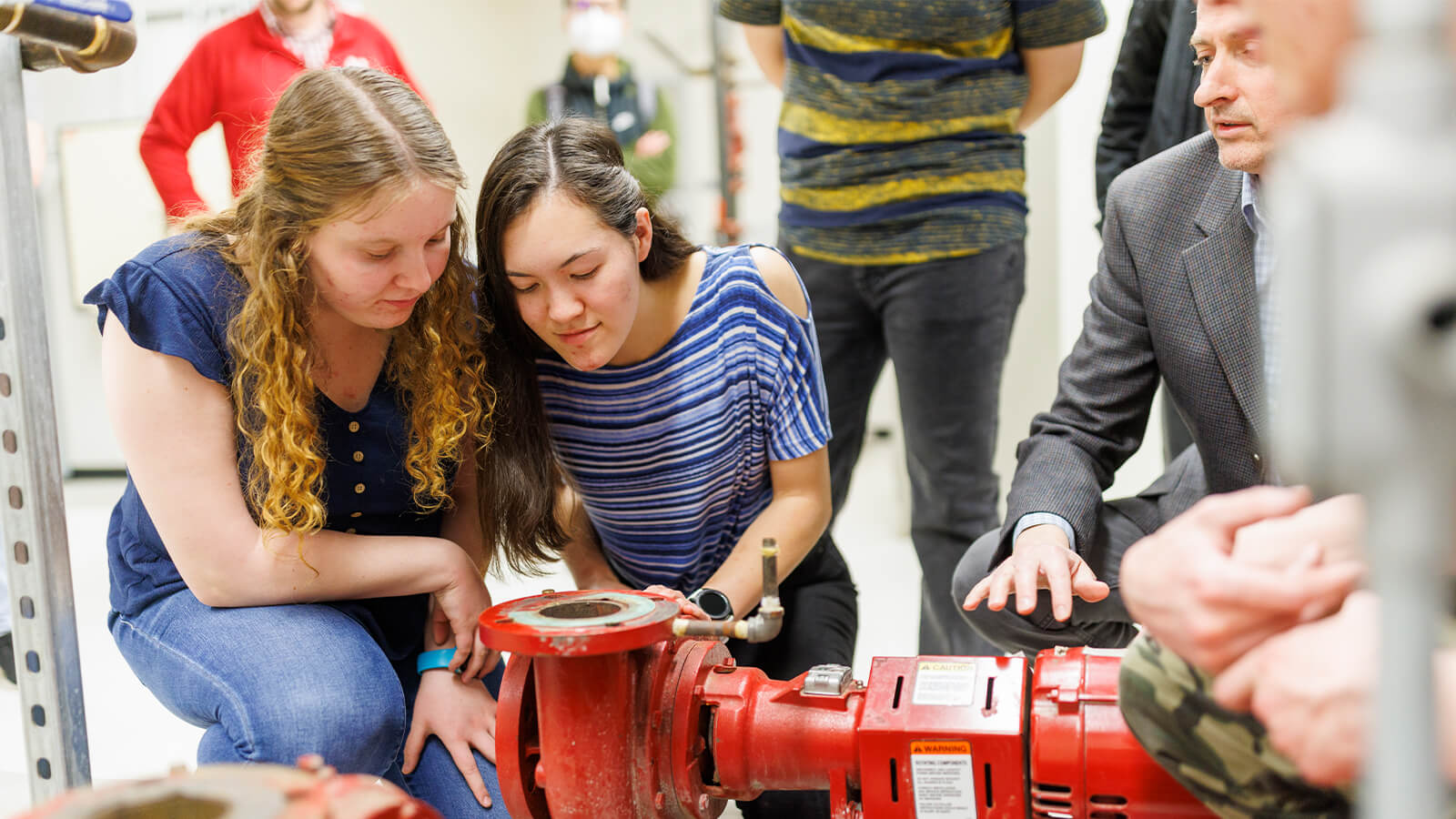 Students examine large release valve on pipe