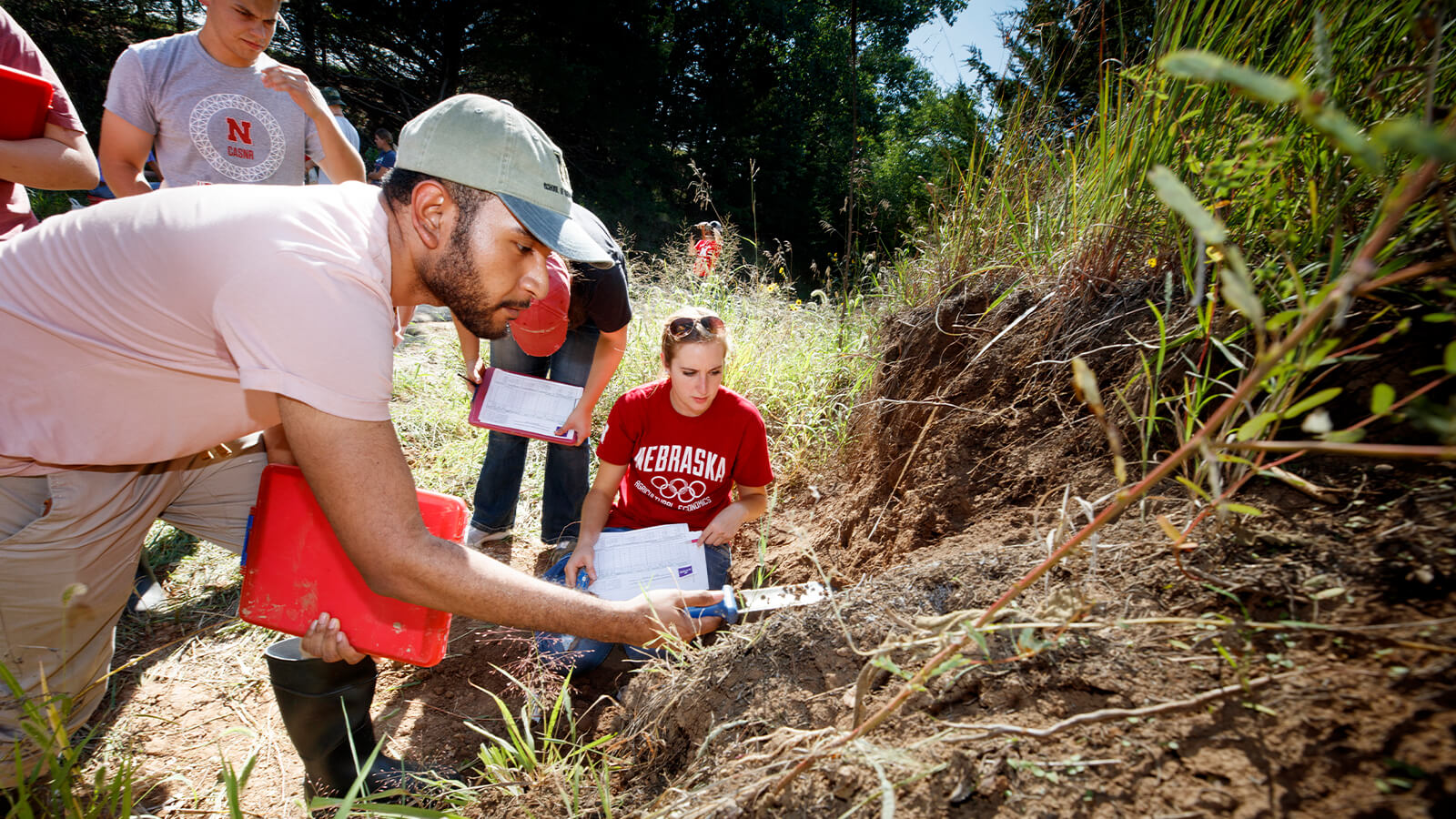A group of students research soil out in the field