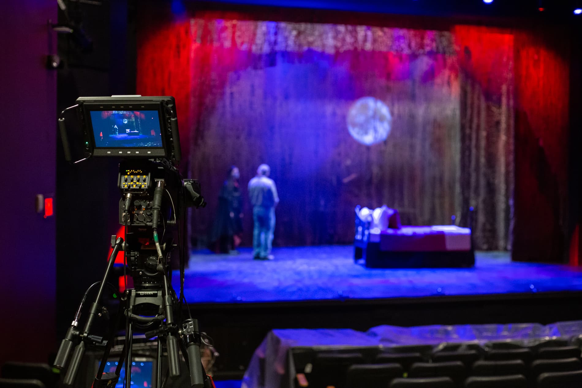 Camera on a tripod pointed at a stage with students on it