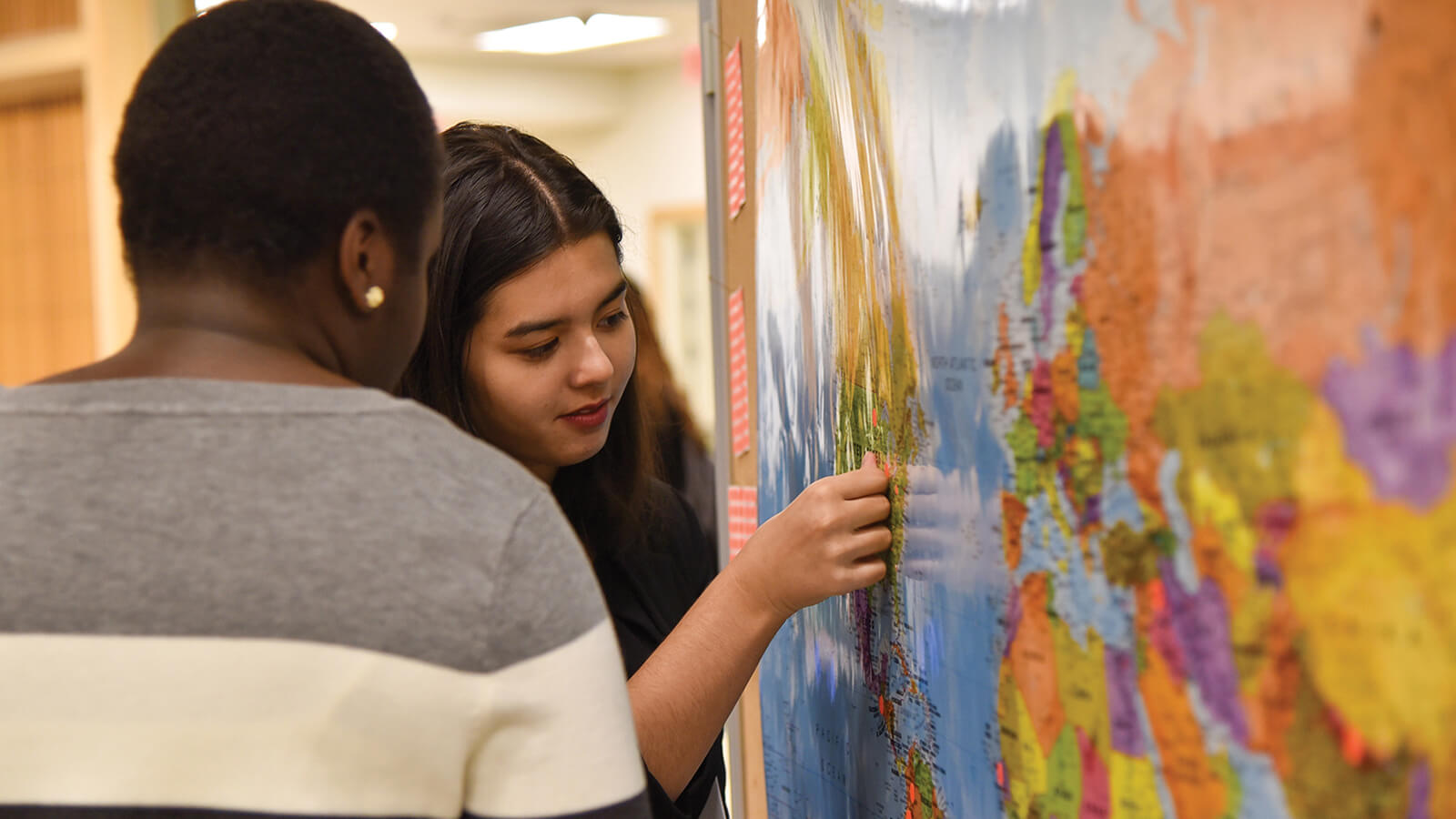Students place marker on world map poster.
