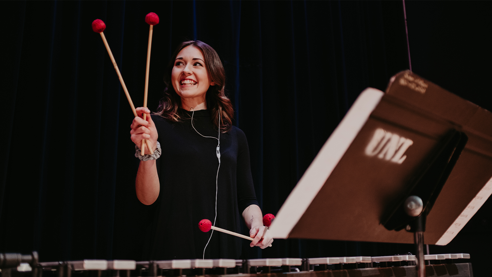 A student smiles while holding mallets