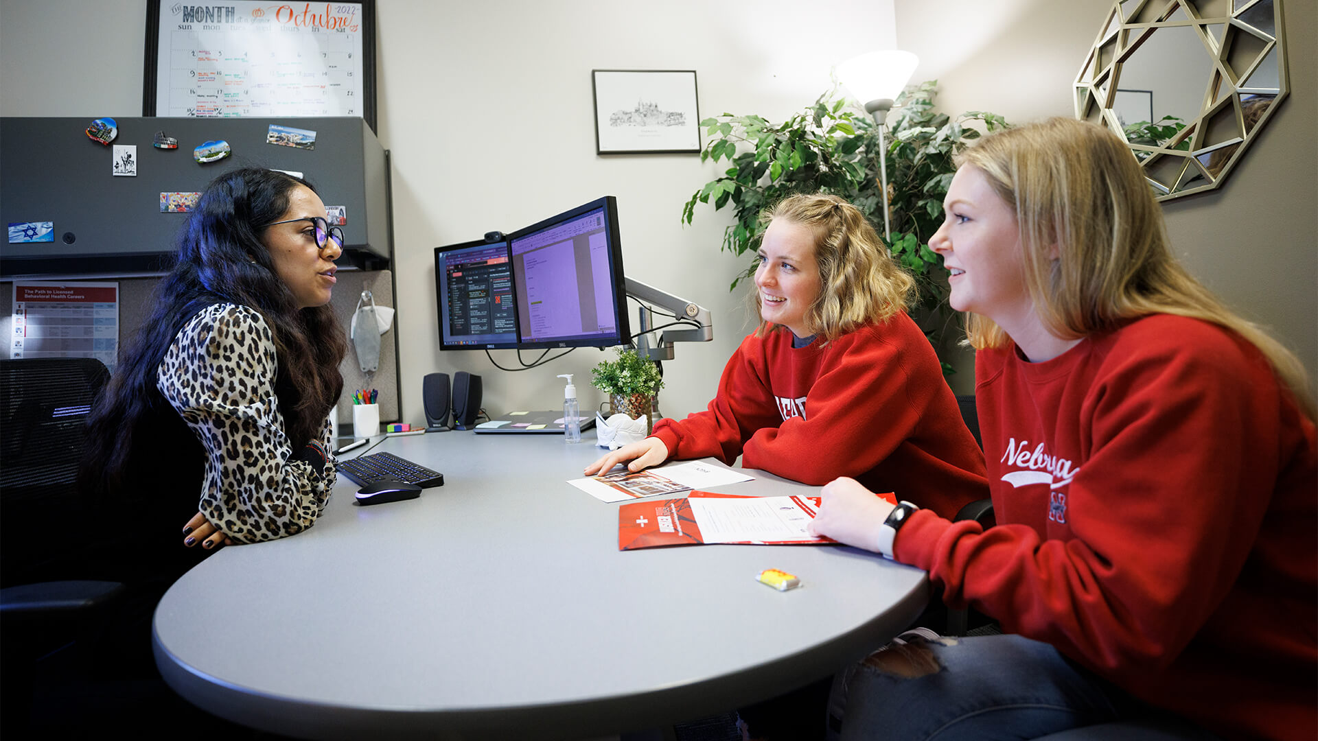 Students meeting with an adviser in an office with a curved desktop