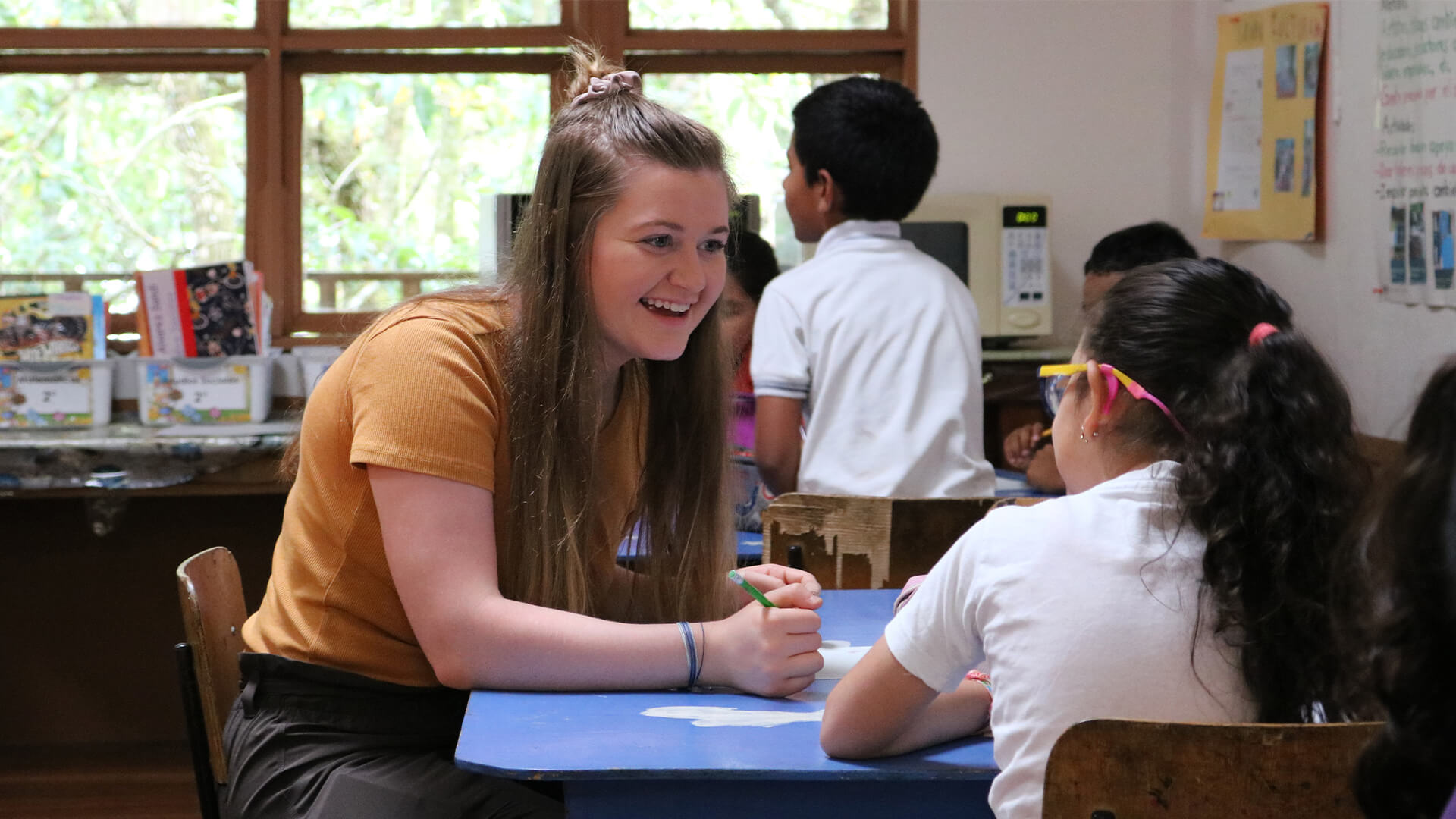 Student talking with elementary student in classroom