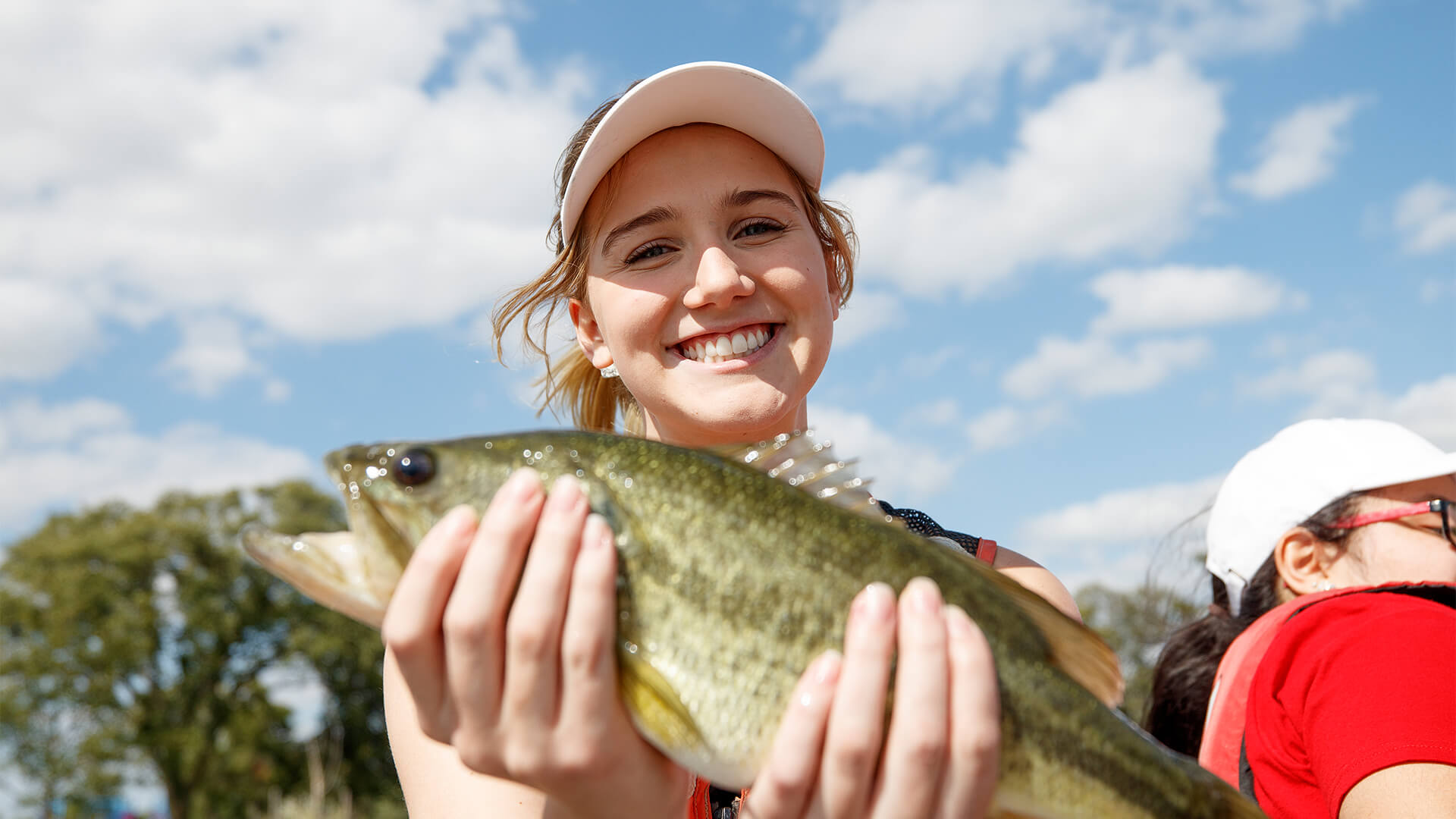 Student holding a fish and smiling