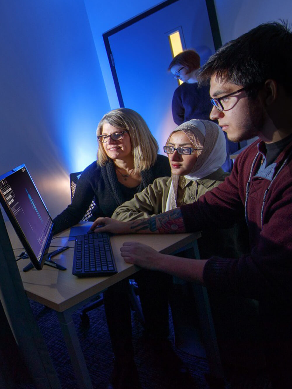 Students and professor study human form on computer screen.
