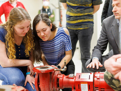 Students examine large release valve on pipe