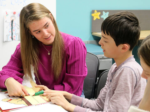Student working with elementary students in classroom