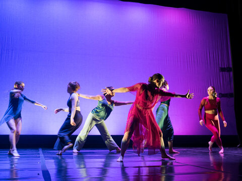Students dance against a purple  blue backdrop