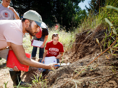 A group of students research soil out in the field