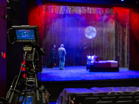Camera on a tripod pointed at a stage with students on it