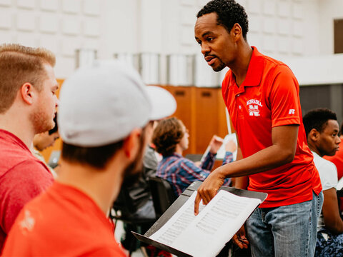 Professor points to sheet music while engaging with student